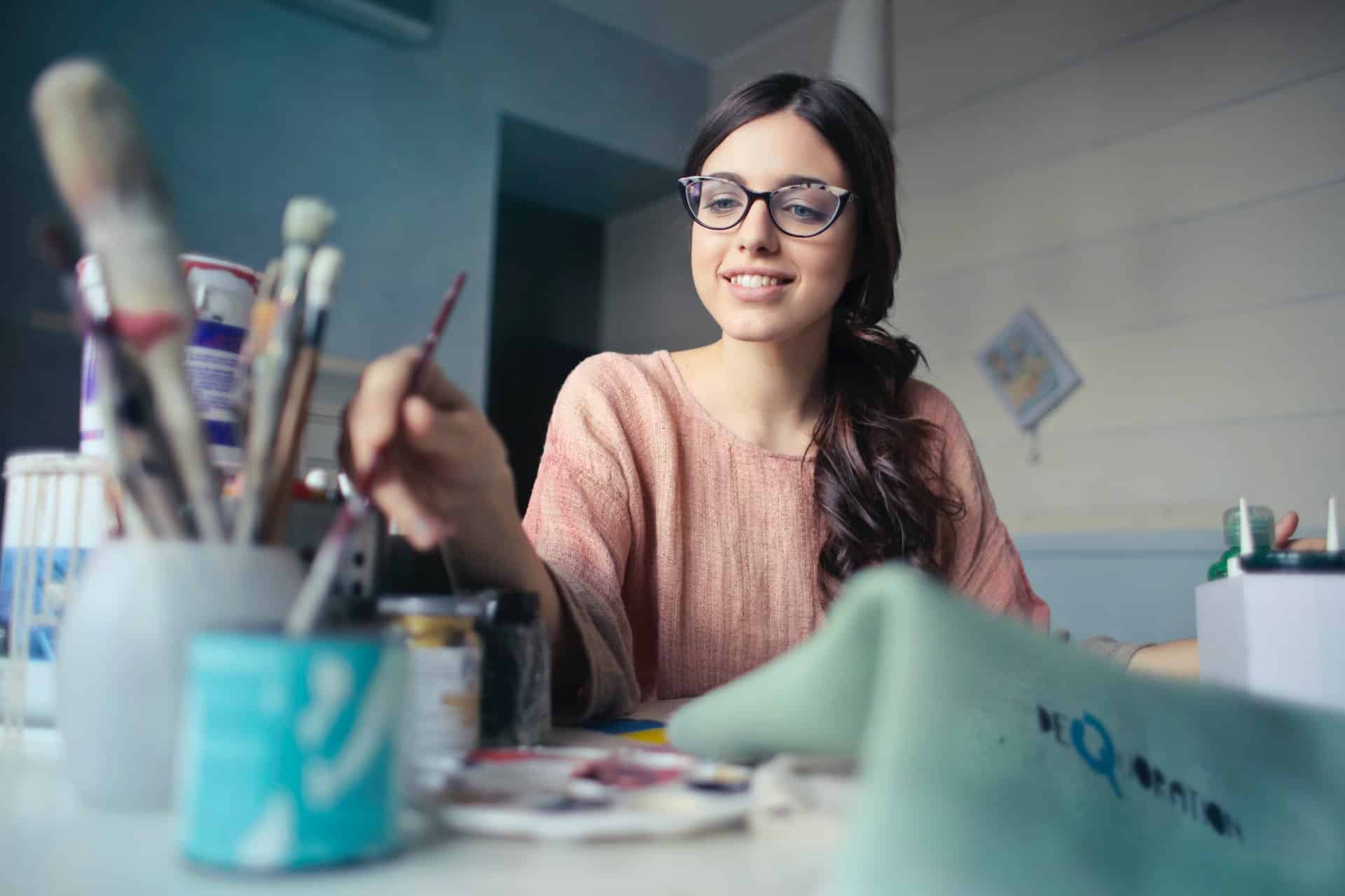 smiling woman practicing expressive art therapy sitting using a paintbrush