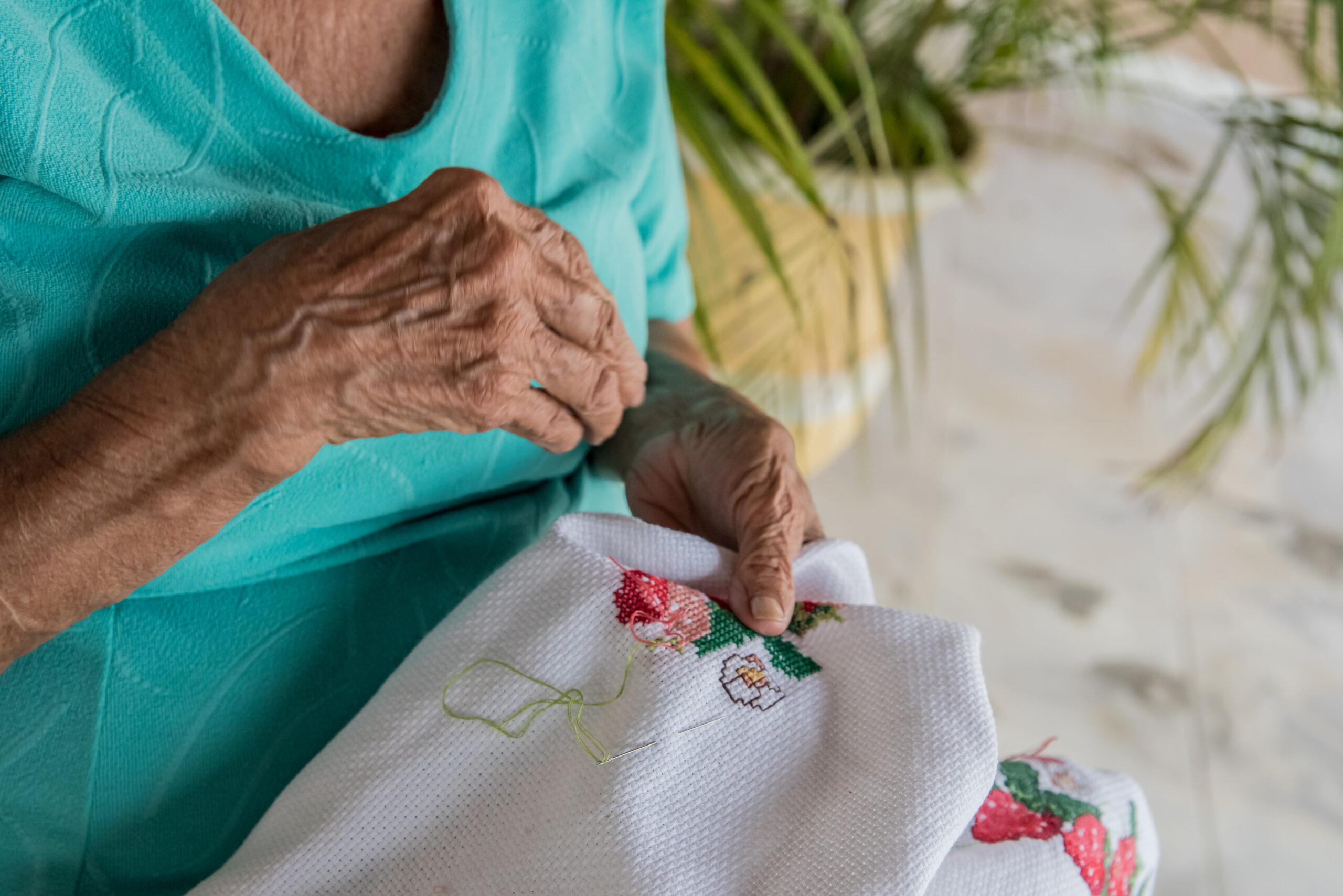 elderly person practicing expressive art therapy embroidering flowers on a fabric
