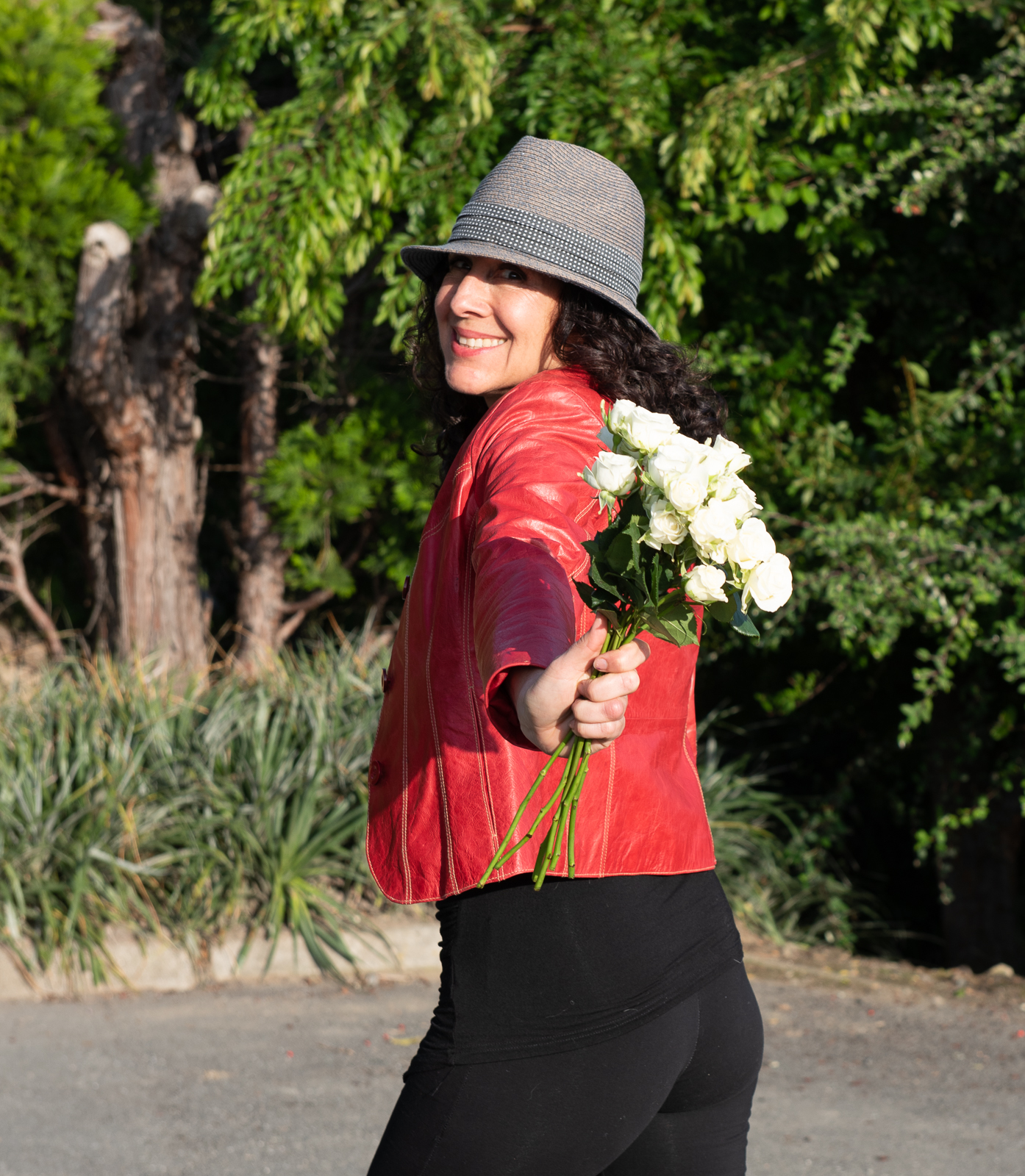 Angela Luna with a bouquet of flowers on the street, smiling.