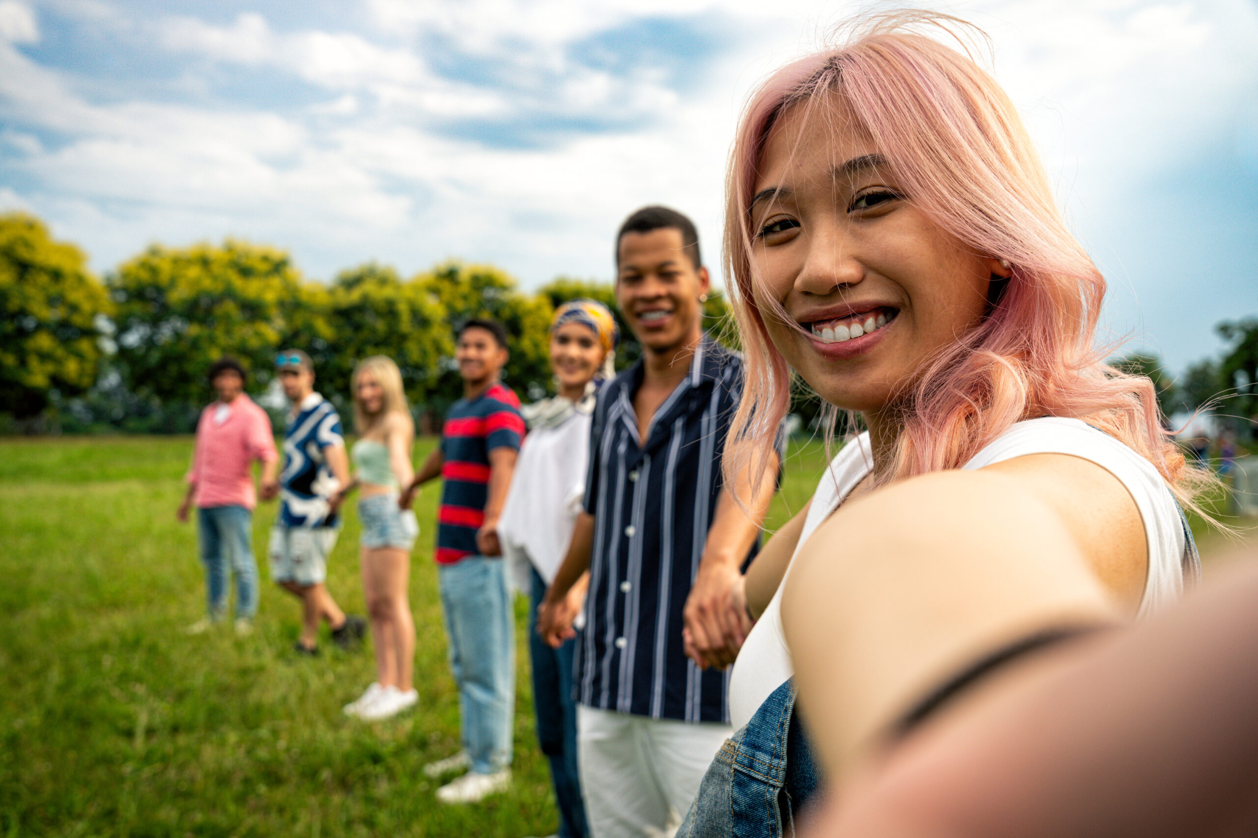 Group of multiethnic teenagers spending time outdoor on a picnic at the park. Concept about generation z, lifestyle and friendship - cultivating joy