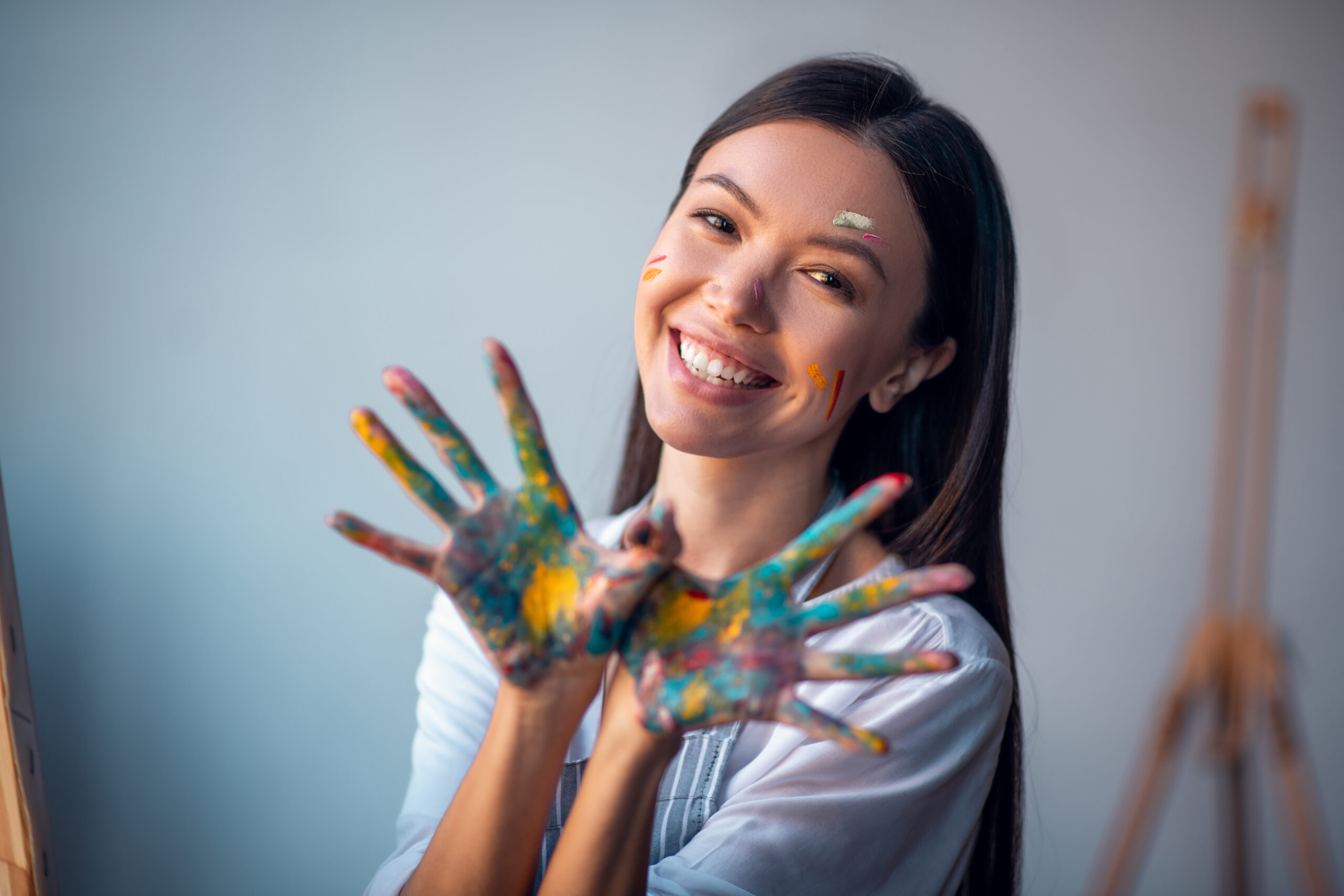 All in paint. Joyful happy woman smiling while showing her hands to you - Cultivating joy